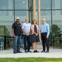 Four people standing in front of CapEd Student Success Center windows