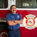 Ryan Veuger stands in front of fire truck with CWI fire academy logo