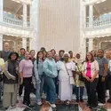 Group of people stand together in front of large signed document in Capitol rotunda
