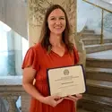 Person holding a certificate in front of staircase