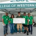Five people stand under a College of Western Idaho tent with a large check