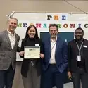 Roxana holding a certificate with three faculty standing beside her