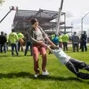 A woman smiles as she spins her son, celebrating in front of a new building being constructed in the background.