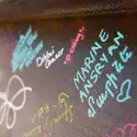 Signatures of various colors on a steel construction beam.
