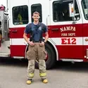 A firefighter poses for a photo in front of a firetruck.