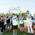 A boy holds up a ceremonial check at a baseball game.