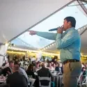 A live auctioneer points to the audience during a benefit auction.