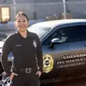 A law enforcement student stands for a portrait in front of a patrol car.
