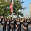 CWI Fire Service Program students saluting the American flag during a ceremony, with uniformed firefighters standing nearby.