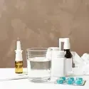 Glass of water, pills and drugs for cold on table