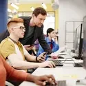 A teacher helps a student at a computer.