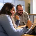 Two people conversing while studying on laptops