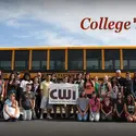 Large group of students holding a CWI sign and standing in front of a bus