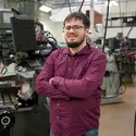 Student stands in front of machine tool technology equipment