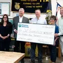 A group of people accept a ceremonial check donation for $250,000.
