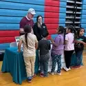 Elementary school students stand at a table and listen to a presentation from College of Western Idaho about STEM subjects.