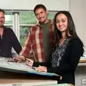 Two entrepreneurs work at a table covered in blue prints alongside a business advisor.