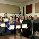 Group of employees with certificates in presidents conference room