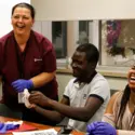 Saint Alphonsus instructor with two happy students learning proper glove techniques