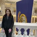 Flora Koenig in front of State of Idaho flag at Idaho State Capitol