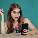 Woman looking at a cell phone with a surprised look