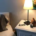 Nightstand next to a bed with glasses, a lamp, and essential oils on it.