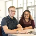 Two students sitting at a desk with a laptop on campus