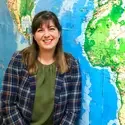 Sarah Strickley leaning against map of world 