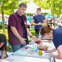 A student signs up for a club at a table display during an outdoor resource fair.