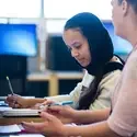 A student receives tutoring at a desk.
