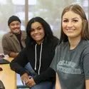 Three students sitting at computers in a classroom