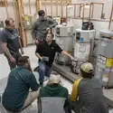 Five students listening to plumbing instructor explain lesson