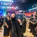 Graduate holding degree and pointing at camera