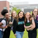 Group of students posing together outside a campus building