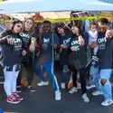 Students dressed in Halloween costumes pose in front of a table with candy on it.
