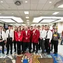 College students pose for a group photo wearing medals that were won during a competition.