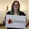 Obendorf holding a print of the 2018 Connections Project logo she designed.