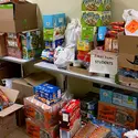 food pantry donations stacked on a table and on the floor