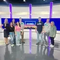 Students touring a TV news station pose for a photo on set. 