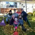 Employees raking up community event posing with leaves and rakes