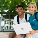 Students sitting outside Nampa Campus Academic Building with a laptop