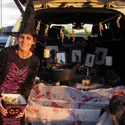 Woman dressed as a witch sitting in a decorated trunk and handing out candy