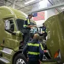 Students stand on the body of a semi truck as they learn about diesel engines.