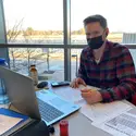 Student wearing a mask studying on campus on a laptop