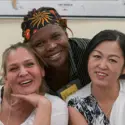 three students of different nationalities smiling at the camera