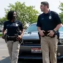 Two public Safety students in front of vehicle in parking lot.