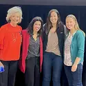 Four women smiling and posing for a photo on a stage