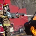 A firefighter puts out a simulated car fire.