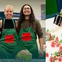 3 people pose for a photo in front a holiday ginger bread house.