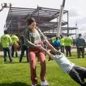 A woman smiles as she spins her son, celebrating in front of a new building being constructed in the background.